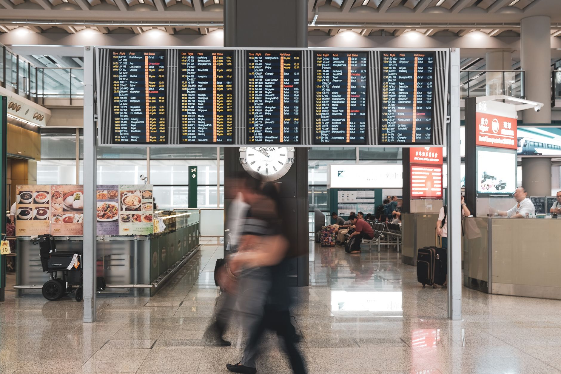 Busy airport departure terminal with travelers carrying luggage, representing international workforce mobility