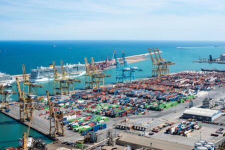 Aerial view of a small regional cargo port with shipping containers and cranes