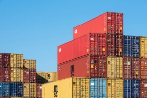 Rows of shipping containers stacked at a busy commercial seaport