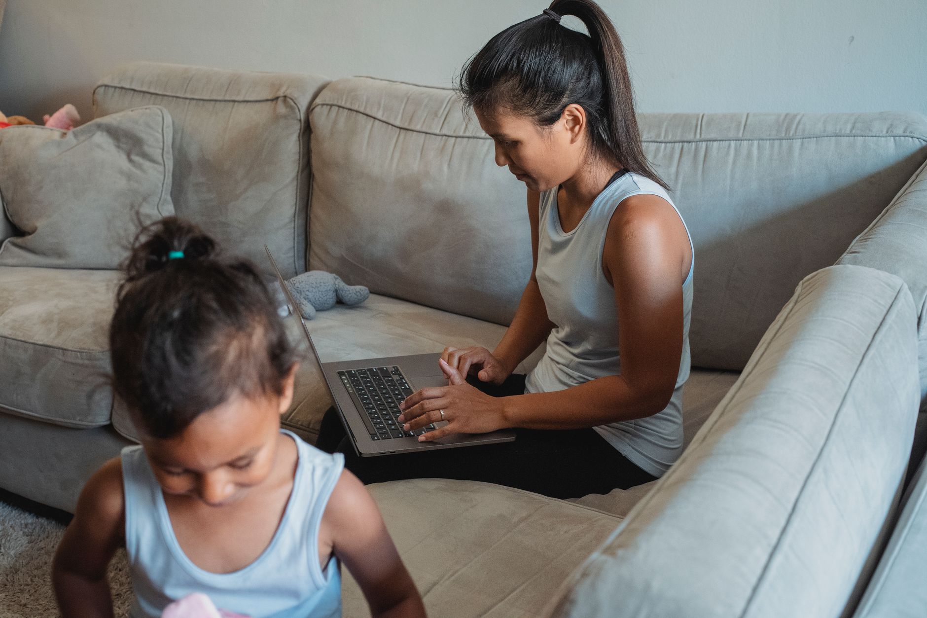 A mother working on a laptop while caring for a young child at home