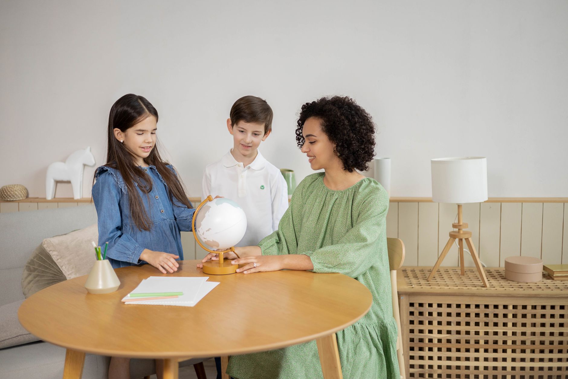 Childcare worker sitting with young children during an activity at a care center