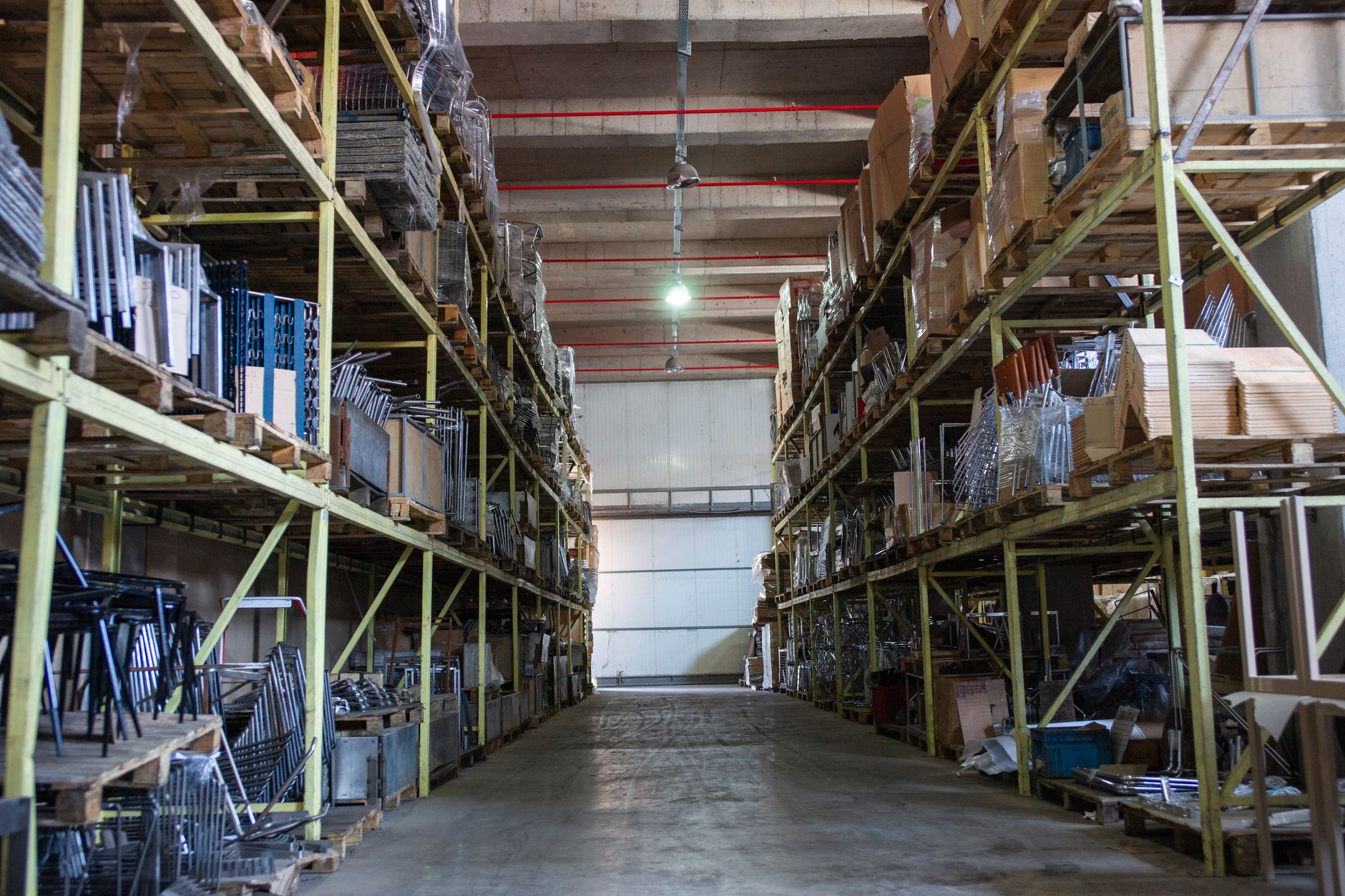 Worker walking through a large warehouse with stacked inventory on shelving