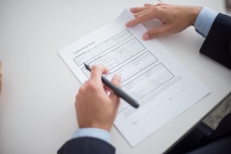 Tenant Screening Fee Surge Quietly Blocks Low-Income Rental Applicants A rental application form on a desk with a pen, representing the tenant screening process