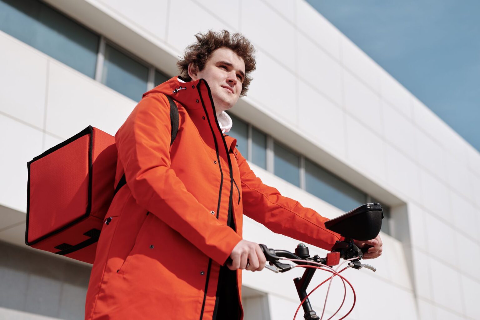 Worker’s Comp Premium Surges Quietly Strain Gig Economy Contractors A gig economy delivery worker on a bicycle checking their phone for work orders
