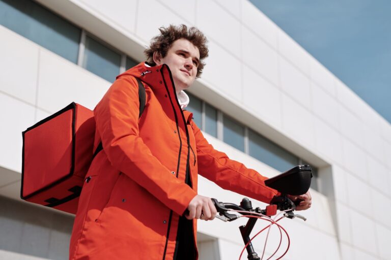 A gig economy delivery worker on a bicycle checking their phone for work orders
