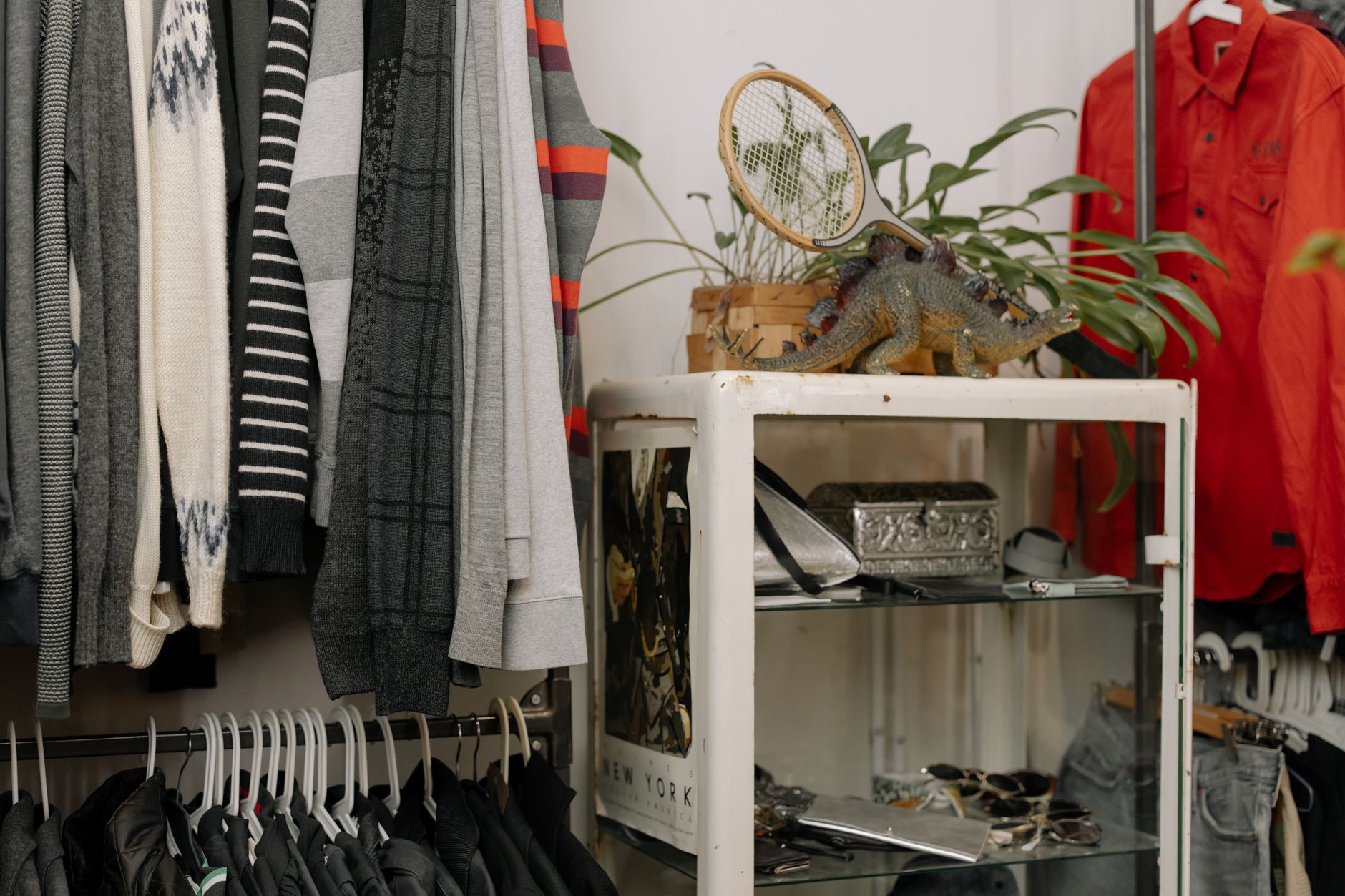 Crowded thrift store clothing racks overflowing with donated items