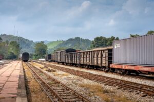 A freight train moving along rail tracks through an industrial corridor
