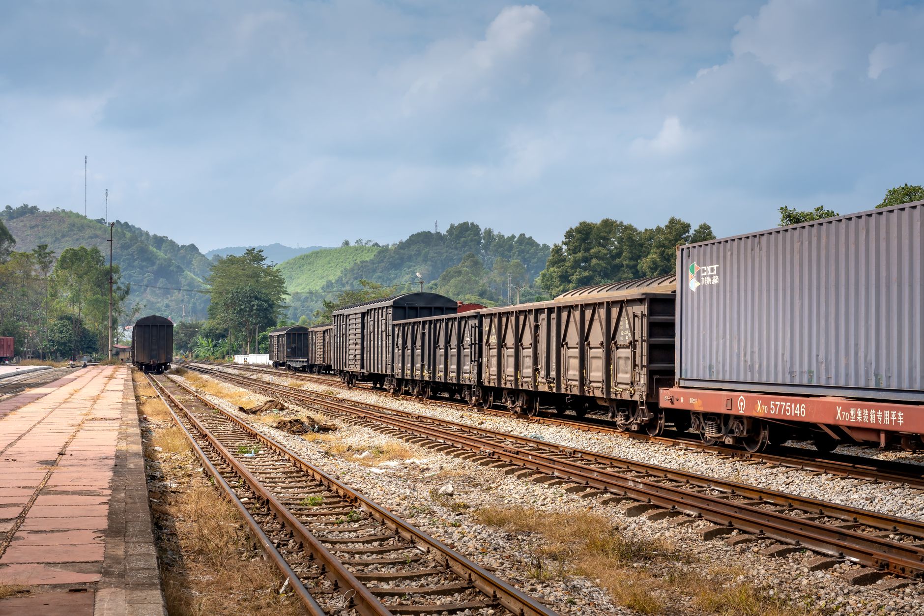 A freight train moving along rail tracks through an industrial corridor