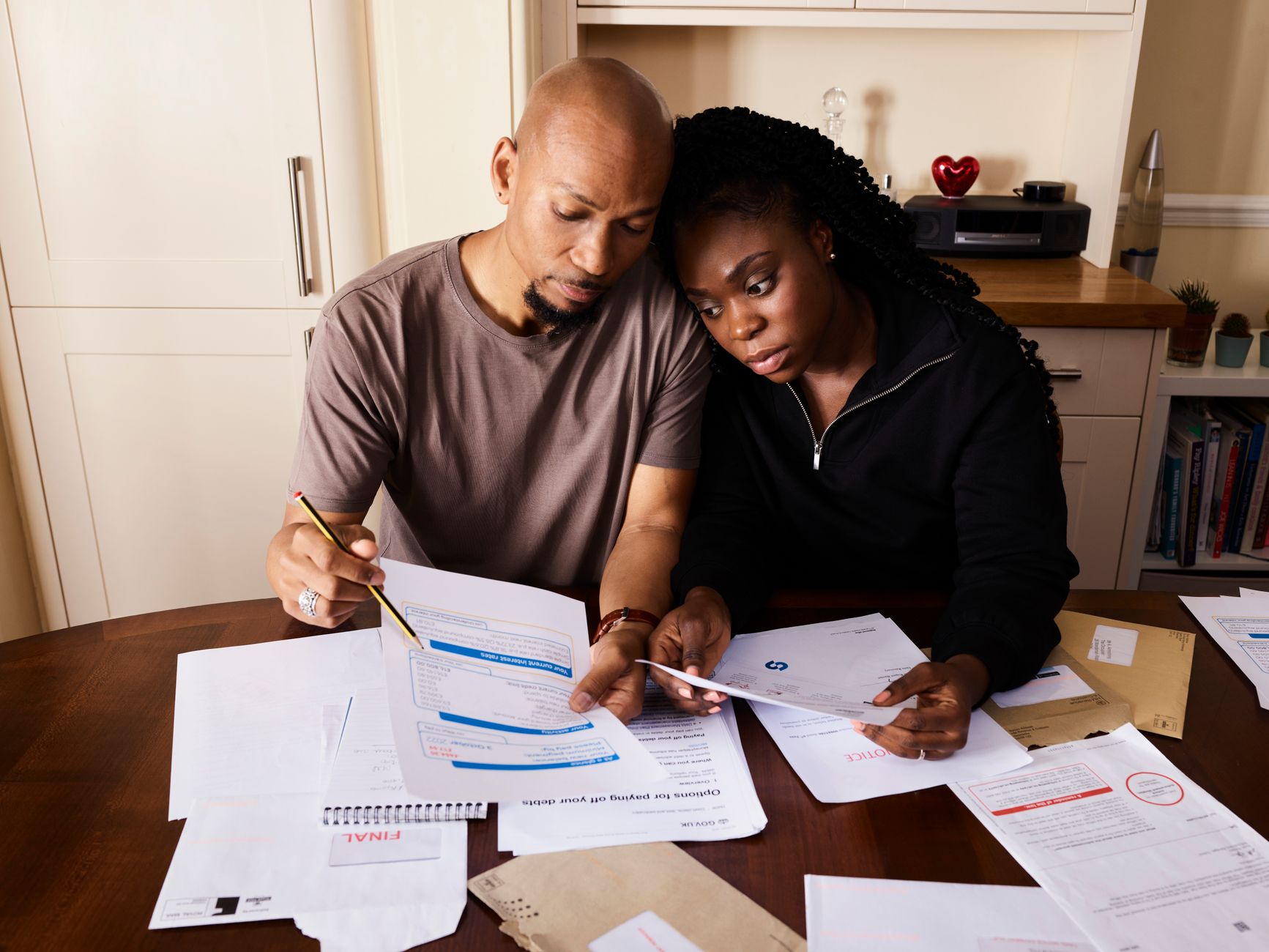 Person reviewing household bills and budget paperwork at a kitchen table
