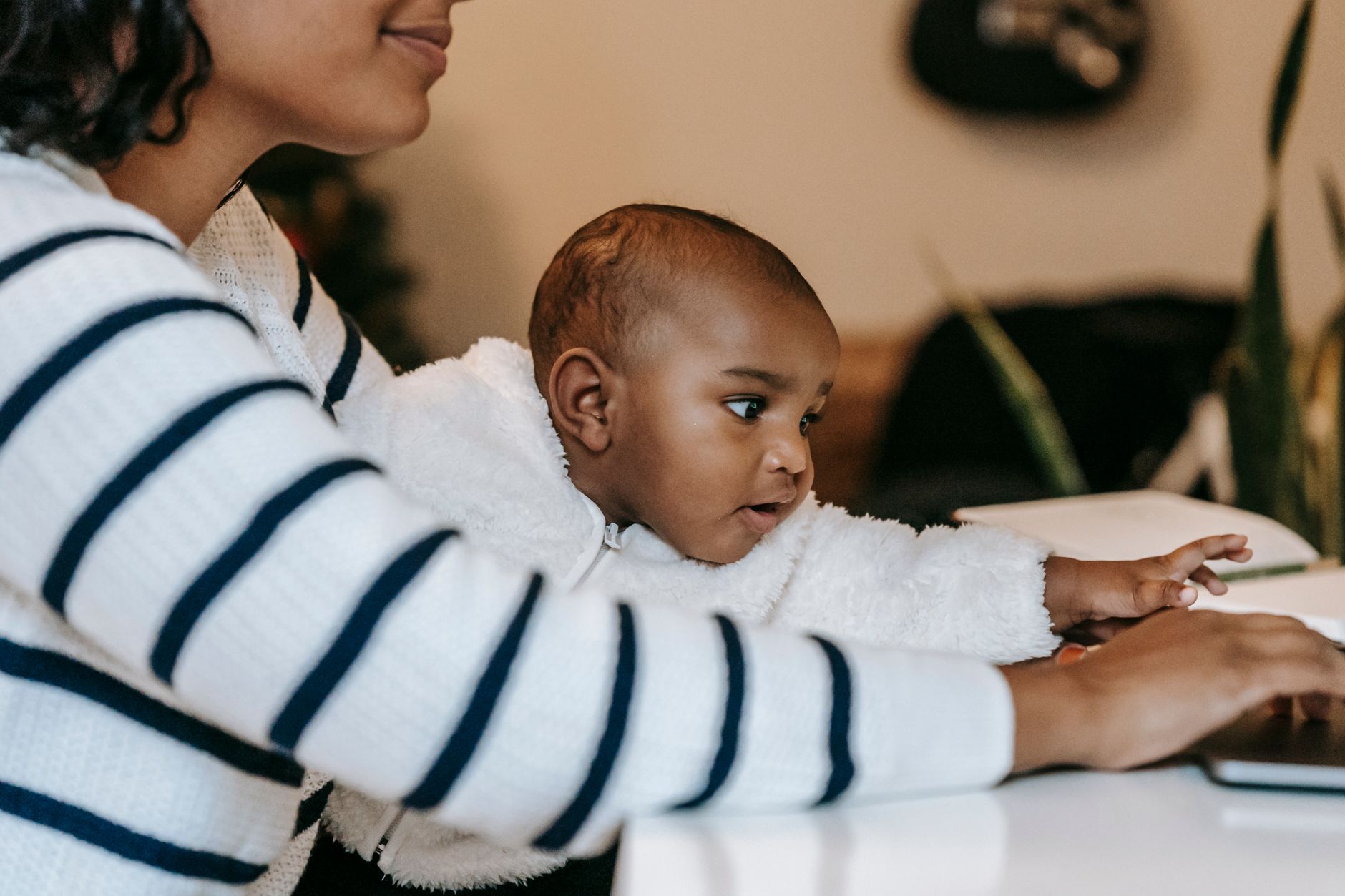 A mother working at a desk while managing childcare responsibilities at home