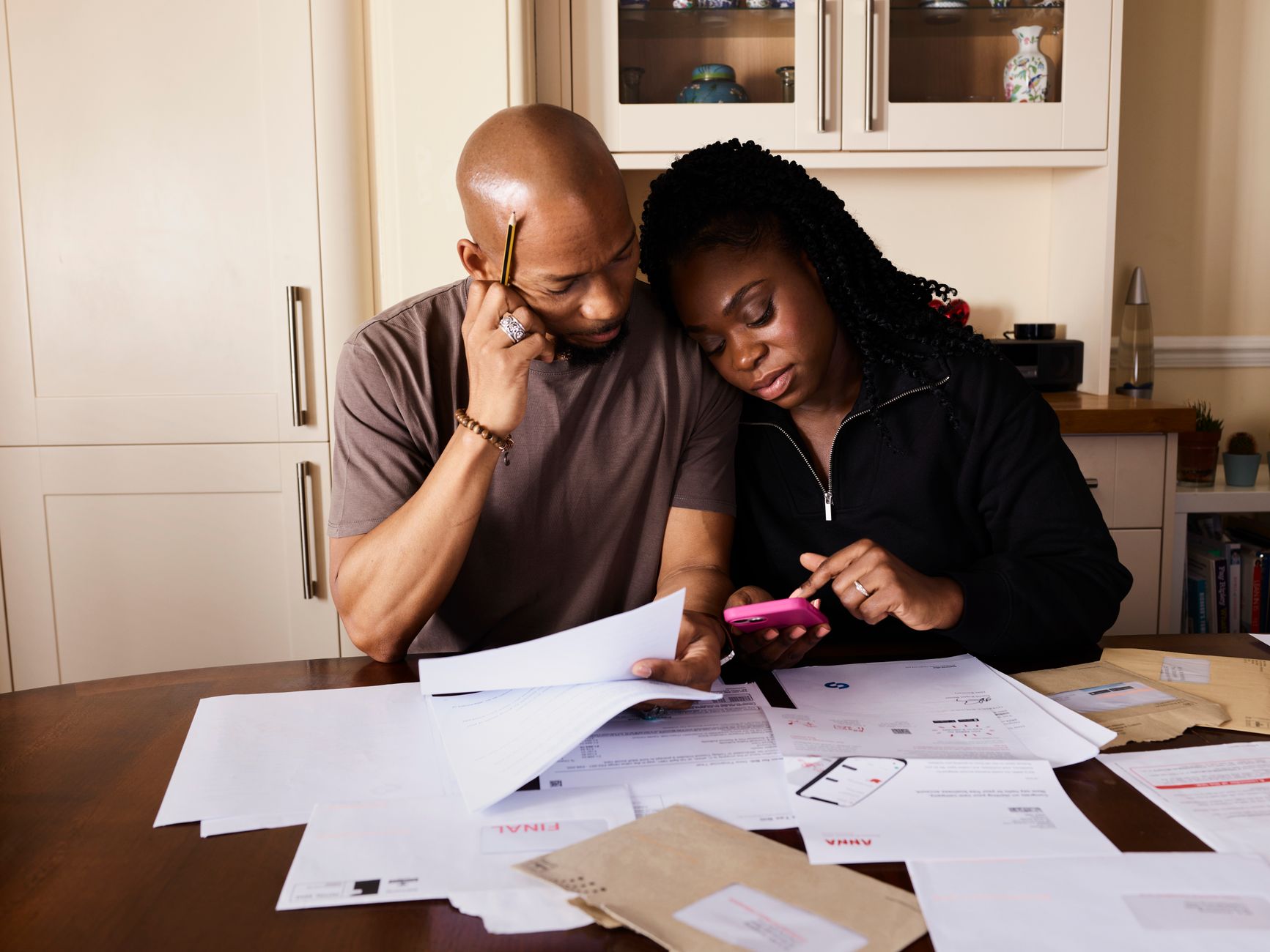Parent reviewing financial documents at a kitchen table, illustrating household budgeting pressures from childcare expenses