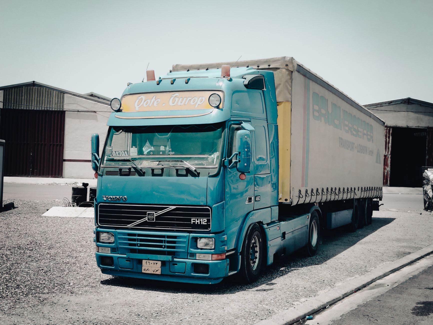 A semi truck parked at a warehouse loading dock in a freight facility